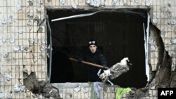 A local resident clears debris from an apartment at a heavily damaged residential building, three days after a Russian missile attack in Kyiv.