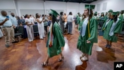 Salutatorian Alasia Baker, 17, center, and Khyli Barbee, 15, following Baker, leave a graduation ceremony for Springfield Preparatory School at Victory in Christ church in Holden, La., Saturday, Aug. 5, 2023. (AP Photo/Matthew Hinton)