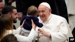 Paus Fransiskus memeluk seorang bayi pada akhir audiensi umum mingguannya di Aula Paulus VI, Vatikan, 28 Februari 2024. (Foto: AP)