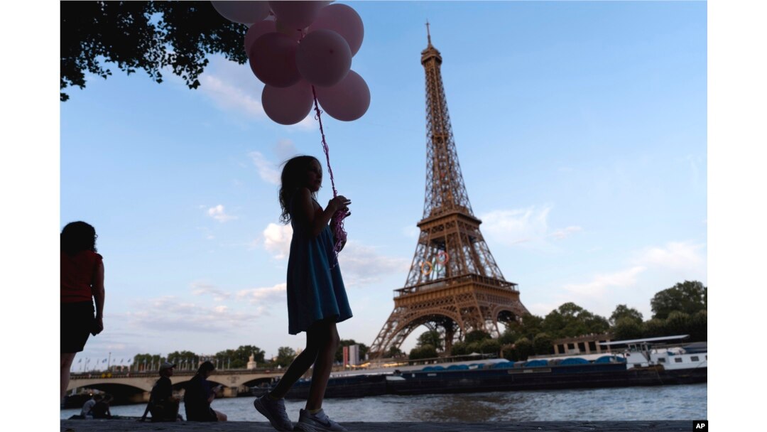 Jenna Baltes, 8, of St. Paul, Minn., holds balloons while walking along the Seine river in front of the Eiffel Tower with her family during the 2024 Summer Olympics, July 29, 2024, in Paris.