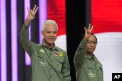 Calon presiden Ganjar Pranowo, kiri, dan pasangannya Mahfud MD memberi isyarat saat tiba untuk debat calon wakil presiden yang disiarkan televisi di Jakarta, 21 Januari 2024. (Foto: AP)