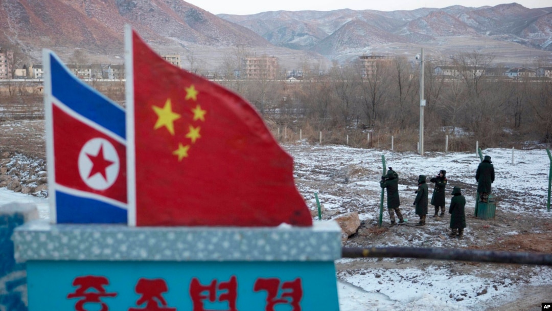 FILE - Chinese paramilitary police build a fence near a concrete marker depicting the North Korean and Chinese national flags with the words "China North Korea Border," at a crossing in Tumen, China, Dec. 8, 2012.