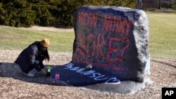 FILE - Michigan State University student Devin Crawford places flowers at The Rock on campus, Feb. 14, 2023, in East Lansing, Mich., after a campus shooting.