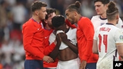 England players comfort teammate Bukayo Saka during the Euro 2020 soccer championship final match between England and Italy at Wembley stadium in London, Sunday, July 11, 2021.(Carl Recine/Pool Photo via AP, File)