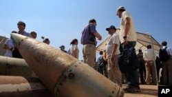 FILE - Activists stand near cluster bombs in Lebanon on Sept. 12, 2011. The United States provided cluster bombs to Kyiv in July 2023.