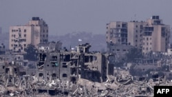 This picture taken from southern Israel shows Israeli flags flying over destroyed buildings inside the Gaza Strip on Nov. 19, 2023,