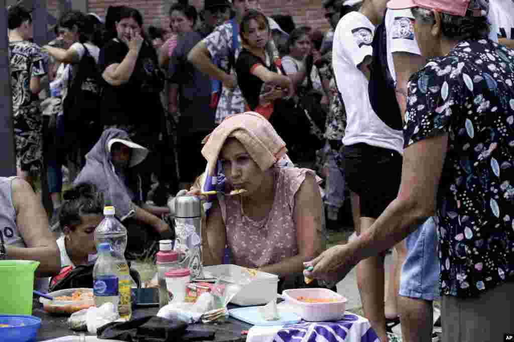  Una manifestante, con una toalla en la cabeza para protegerse del sol, come comida comunitaria servida durante una protesta contra las medidas de austeridad propuestas por el presidente de Argentina, Javier Milei, en La Matanza, en las afueras de Buenos Aires, Argentina, el 17 de enero de 2024. Milei ha anunciado medidas económicas con la esperanza de evitar la hiperinflación. (Foto AP/Rodrigo Abd) &nbsp; 