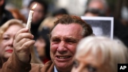 FILE - A man cries as he holds up a candle on the 25th anniversary of the bombing of the AMIA Jewish center that killed 85 people in Buenos Aires, Argentina, July 18, 2019. 