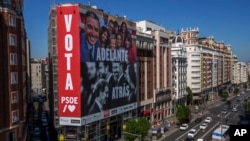 Poster kampanye raksasa yang menggambarkan PM Spanyol dan kandidat Sosialis Pedro Sánchez, atas, dan pemimpin partai konservatif PP Alberto Nunez Feijóo serta pemimpin partai sayap kanan VOX Santiago Abascal terlihat di ibu kota Madrid.