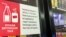 FILE - A sign posted on a drink cooler in a store gives information about a soda tax, in Seattle, Washington, Sept. 24, 2018. The WHO said hiking taxes on sugary drinks could result in healthier populations. 