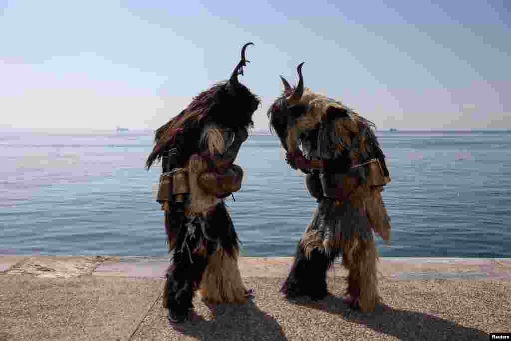 Participants stand by the seaside during the 6th European Festival of Bell-bearing traditions in Thessaloniki, Greece.