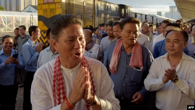 FILE - Cambodian Minister of Public Works and Transport Sun Chanthol, center left, and tycoon Kith Meng, right, chairman of The Royal Group gestures on arrival in Phnom Penh railway station on July 4, 2018.