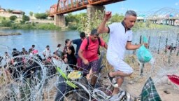 Migrantes cruzan de manera irregular sobre el alambre de púas hacia Eagle Pass, Texas, con la intención de ser procesados por autoridades fronterizas el 25 de septiembre de 2023.