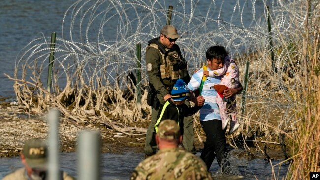 FILE - Migrants are taken into custody by officials at the Texas-Mexico border, in Eagle Pass, Texas, Jan. 3, 2024.