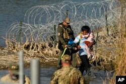 FILE - Migrants are detained by U.S.-Mexico border officials in Eagle Pass, Texas, January 3, 2024.