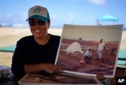 Malia Nobrega-Olivera memperlihatkan foto kakek dan neneknya sedang membuat garam Hawaii, atau "paakai", sambil duduk di Salt Pond Beach Park di Hanapepe, Hawaii, Minggu, 10 Juli 2023. (AP/Jessie Wardarski)