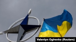 Украинский флаг поднимается перед эмблемой НАТО в центре Киева, Украина (архивное фото). REUTERS/Валентин Огиренко