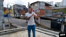 FILE - Influencer Murilo Duarte streams a live video at the Jardim João XXIII slum in Sao Paulo, Brazil, on April 19, 2023. 