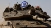 Tentara Israel memegang bendera Israel, saat mereka mengendarai tank Merkava, dekat perbatasan Israel setelah meninggalkan Gaza, selama gencatan senjata sementara antara Hamas dan Israel, di Israel, 24 November 2023. (Foto: REUTERS/Amir Cohen)