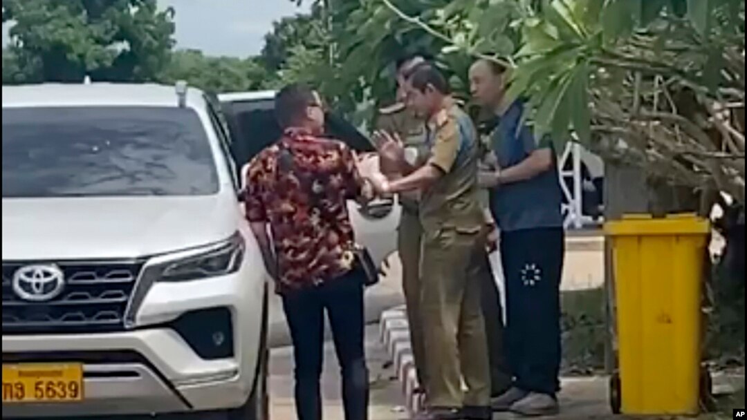 FILE - In this image from a source wishing to remain anonymous, an activist, at left, traveling with Chinese rights lawyer Lu Siwei, right, argues with police who were detaining Lu, near the Thanaleng dry port, south of Vientiane, Laos, July 28, 2023.