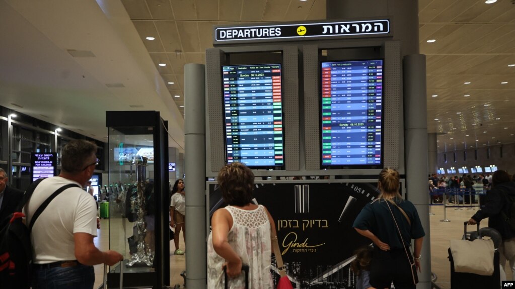 2023年10月7日，在以色列特拉维夫附近的本古里安机场，乘客们看着登机牌，因为哈马斯的突然袭击，航班被取消。(法新社， 2023年10月7日)(photo:VOA)