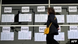 A woman walks by a window displaying electoral rolls at a polling station in Buenos Aires, during the presidential election runoff on Nov. 19, 2023. 