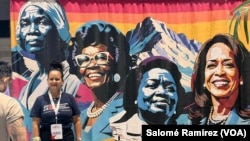 Asistentes a la Convención Nacional Demócrata en Chicago se toman fotos frente a un mural que incluye la imagen de Kamala Harris. 