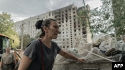 A resident cleans debris around a heavily damaged residential building following a recent missile attack in Kharkiv, on Aug. 31, 2024.