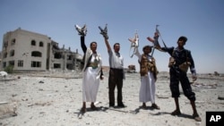 FILE - Shiite fighters, known as Houthis, hold up their weapons as they chant slogans at the residence of a military commander of the Houthi militant group, destroyed by a Saudi-led airstrike in Sanaa, Yemen, April 28, 2015.