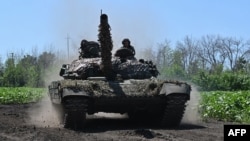 Ukrainian servicemen ride on a tank not far from the front line in Ukraine's Kharkiv region on July 6, 2023.