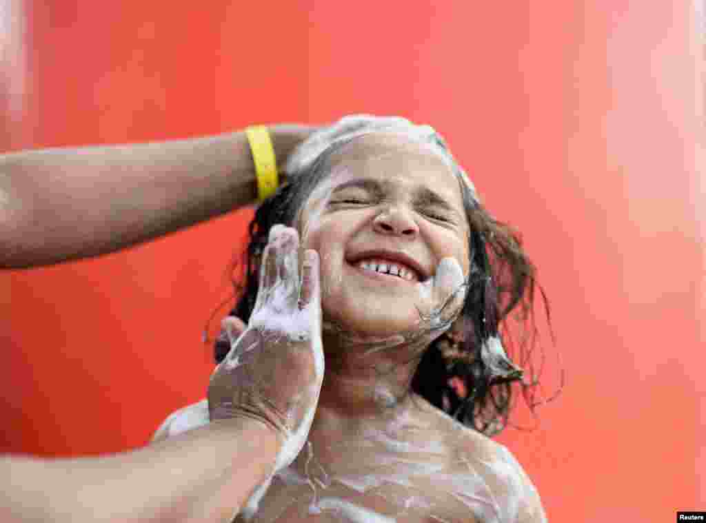 A Rohingya Muslim girl reacts while taking a bath at a port warehouse that is used as a temporary shelter in Sabang, Aceh province, Indonesia.