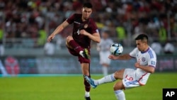 El venezolano Jhon Chancellor, izquierda, y el chileno Alexander Aravena luchan por el balón durante un partido de fútbol de clasificación para la Copa Mundial de la FIFA 2026 en el estadio Monumental de Maturín, Venezuela, el martes 17 de octubre de 2023.