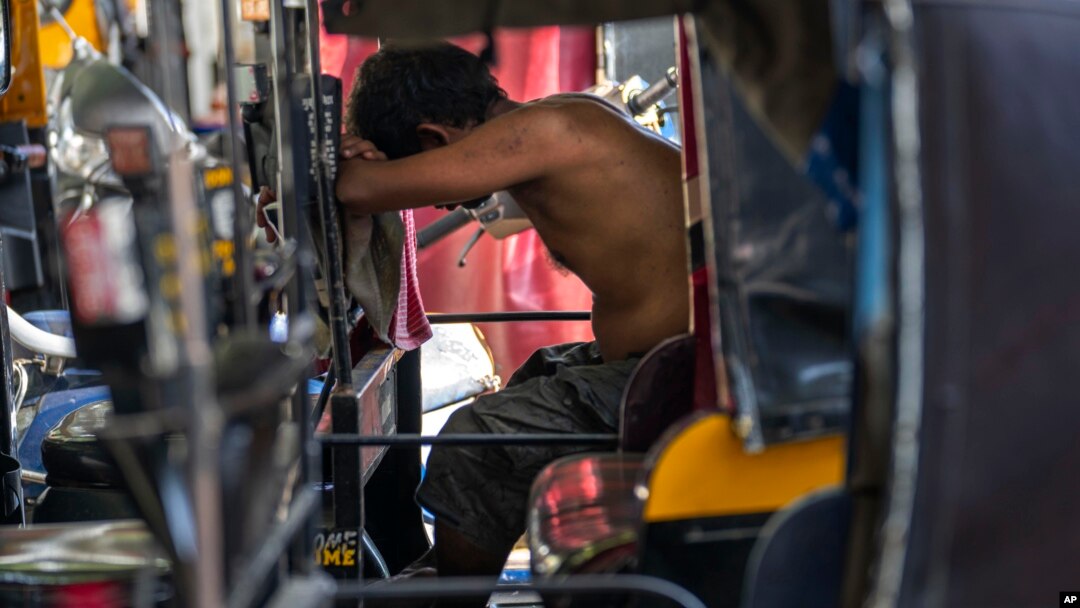 A driver takes a nap on a hot afternoon in his auto-rickshaw in Mumbai, India, June 11, 2023. 