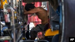 A driver takes a nap on a hot afternoon in his auto-rickshaw in Mumbai, India, June 11, 2023. 