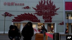 Shoppers wait for their ride near a store decorated with a dragon motif ahead of the lunar Year of the Dragon in Beijing, Jan. 22, 2024. 