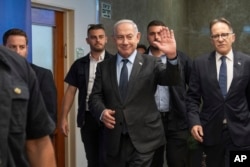 Israeli Prime Minister Benjamin Netanyahu, center, waves to the media as he arrives to the cabinet meeting at the prime minister's office in Jerusalem, July 17, 2023.