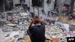 A child reacts as people salvage belongings amid the rubble of a damaged building following strikes on Rafah in the southern Gaza Strip, Nov. 12, 2023.