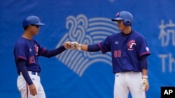 Two Taiwanese plays bump fists during men's baseball game on Oct. 3, 2023, against Hong Kong at the Asian Games in Hangzhou, China, where Taiwan's athletes are competing under the name Chinese Taipei. 