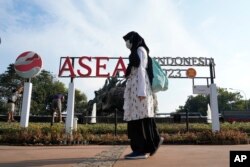 Seorang pejalan kaki melintas di depan logo Perhimpunan Bangsa-Bangsa Asia Tenggara atau ASEAN ( Association of Southeast Asian Nations) di Jakarta, 10 Juli 2023. (Foto: Achmad Ibrahim/AP Photo)