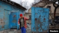 A woman stands next to a house damaged by recent shelling in the course of Russia-Ukraine conflict in Donetsk, Russian-controlled Ukraine, Jan. 7, 2024. 