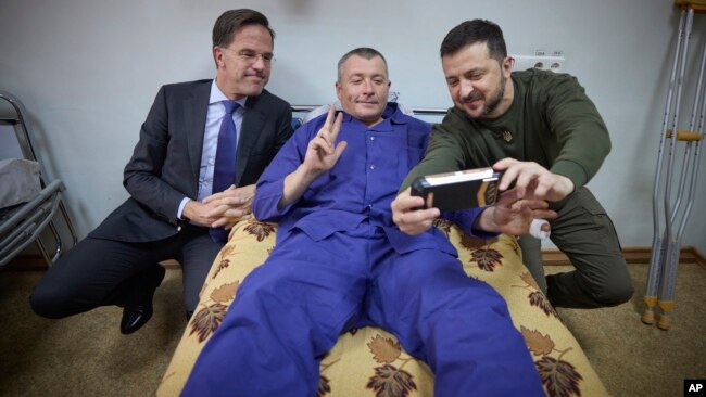 Ukrainian President Volodymyr Zelenskyy, right, and Netherland's caretaker Prime Minister Mark Rutte pose for a photo with a wounded Ukrainian soldier in a hospital in Odesa, Ukraine, on Oct. 13, 2023. (Ukrainian Presidential Press Office via AP)