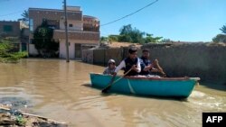 Residents row a boat to cross a flooded street after heavy rains in Gwadar in Balochistan province on March 2, 2024.