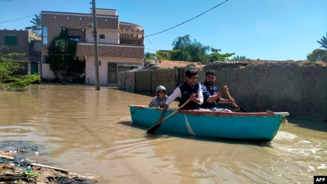 Residents row a boat to cross a flooded street after heavy rains in Gwadar in Balochistan province on March 2, 2024.