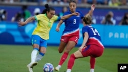 Brazil's Marta, left tries to get past U.S. players Mallory Swanson, center, and Emily Sonnett during the women's soccer gold medal match at the Parc des Princes, Aug. 10, 2024, in Paris, France.