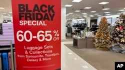 A sign announces Black Friday specials on luggage sets inside a Macy's department store Nov. 20, 2023, in Denver. 