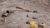 A man walks past construction vehicles covered in debris caused by flash floods after a lake burst in Rangpo, Sikkim state, India, Oct. 8, 2023. 