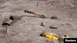 A man walks past construction vehicles covered in debris caused by flash floods after a lake burst in Rangpo, Sikkim state, India, Oct. 8, 2023. 