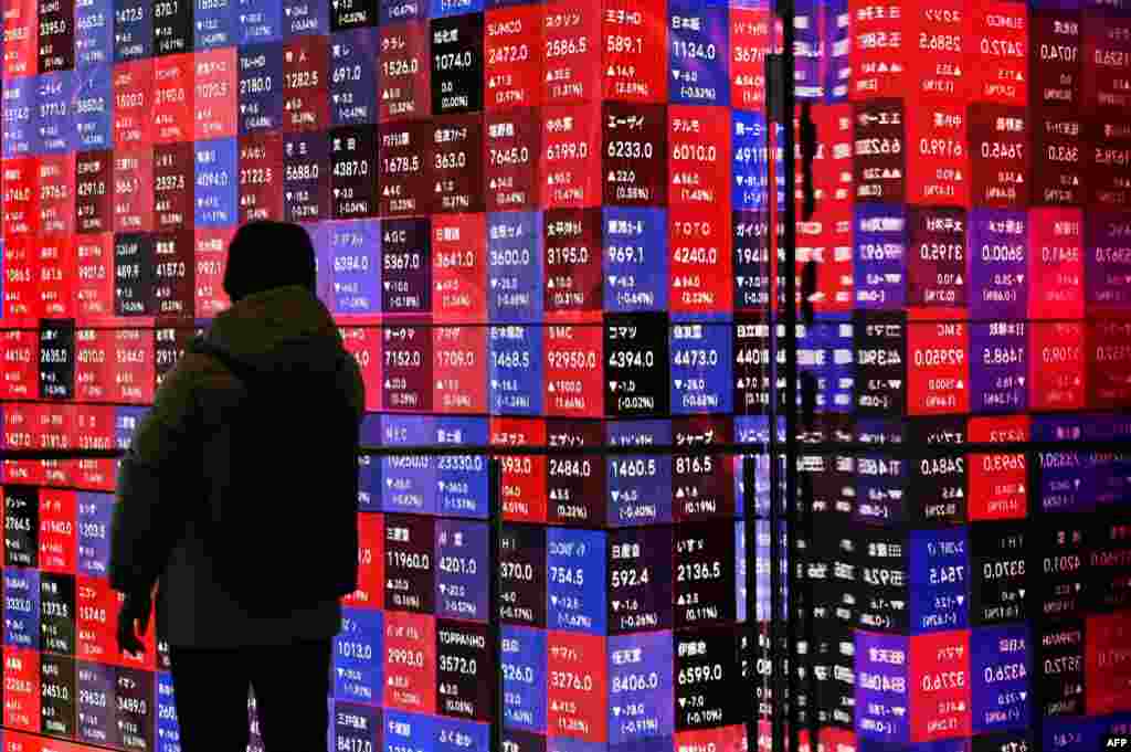 A man looks at an electronic boards displaying stock prices of companies listed on the Tokyo Stock Exchange in Tokyo.