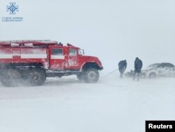 Los trabajadores de emergencia liberan un automóvil que quedó atrapado en la nieve durante una fuerte tormenta de nieve en la región de Odesa, Ucrania, en esta fotografía publicada el 27 de noviembre de 2023.