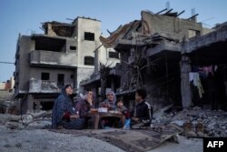 The Palestinian Al-Naji family eats an iftar meal, the breaking of fast, amidst the ruins of their family house, on the first day of the Muslim holy fasting month of Ramadan, in Deir el-Balah in the central Gaza Strip on March 11, 2024.